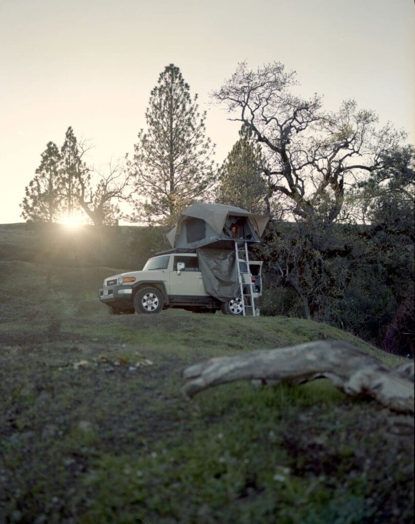 Car with rooftop camper tent, customized at a custom car shop for adventure-ready performance